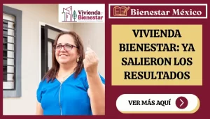 Mujer consulta en su celular el estatus de su registro de Vivienda para el Bienestar frente a un conjunto de casas nuevas